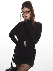 Woman wearing a black long-sleeve mini dress, star-patterned tights, and glasses, striking a pose.