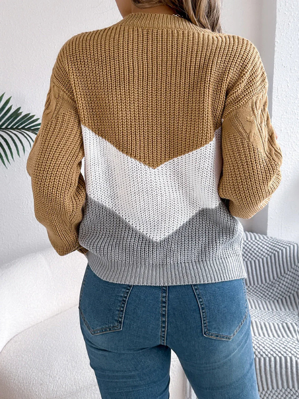 Back view of a woman wearing a brown, white, and grey colorblock chevron knit sweater