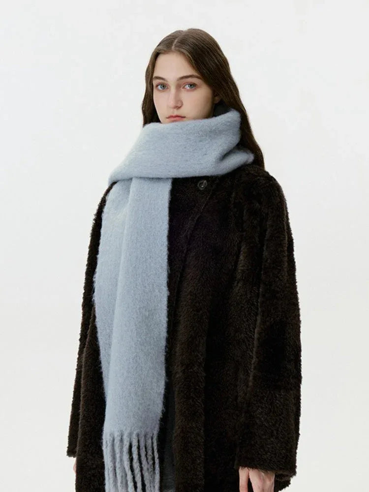 Portrait of a woman in a dark fuzzy coat and a light blue scarf, facing forward.