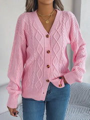 front view of a woman wearing a pink cable knit cardigan with a v-neckline and button-down closure, paired with blue jeans