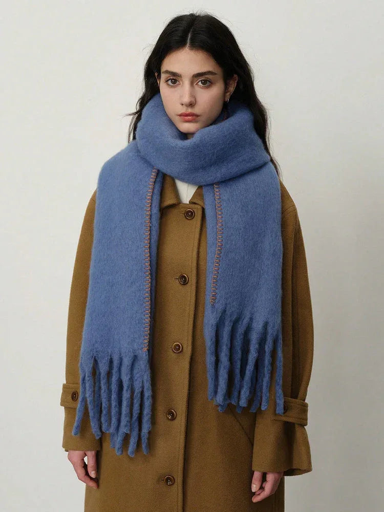 Woman wearing a blue fringed scarf draped over a brown coat