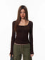 Woman wearing a brown long-sleeved top with decorative studs and olive green cargo pants.