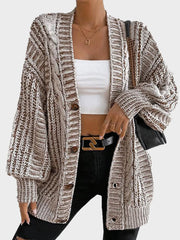 Model wearing a brown and white striped oversized knit cardigan with a white crop top and black jeans