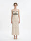 Woman wearing a cream knit maxi dress with black stripes on the bust, shown front view on a white background.