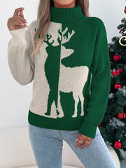 Close-up of a woman wearing a green and cream knit sweater with a reindeer graphic and a turtleneck.