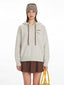 Close-up of the model's upper body, showcasing the speckled knit hoodie with graphic detail on the chest and decorative drawstrings.