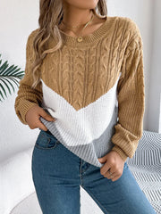 Close-up of a woman wearing a brown, white, and grey colorblock chevron knit sweater, tucking it into her jeans