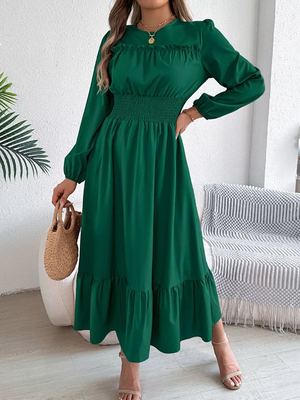woman wearing a long green dress with long sleeves and a smocked waist