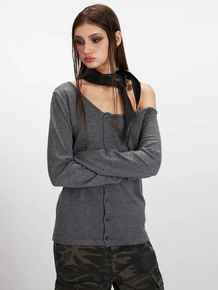 Model posing with arms crossed in a grey off-the-shoulder knit top and camouflage cargo pants.