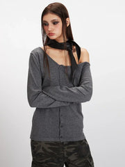 Model posing with arms crossed in a grey off-the-shoulder knit top and camouflage cargo pants.