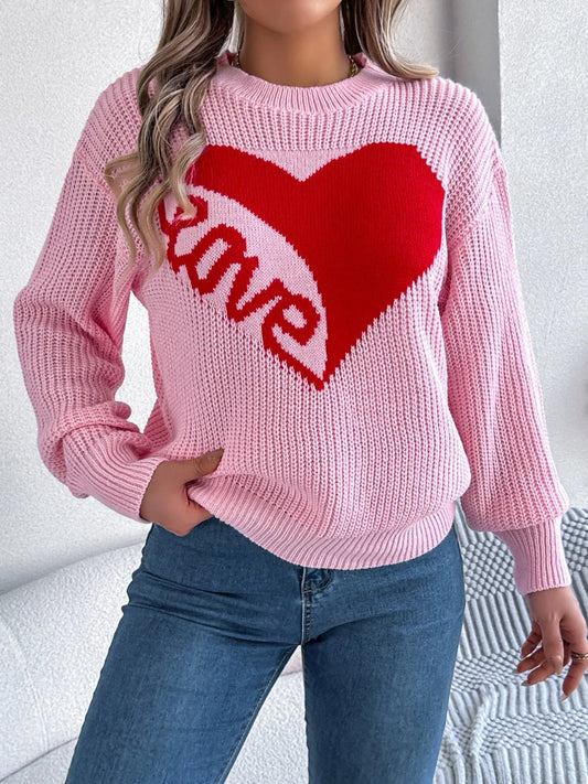 Woman wearing a pink knit sweater with a red heart graphic and the word "love" on the front.