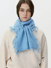 Woman wearing a light blue knitted scarf with fringe details.