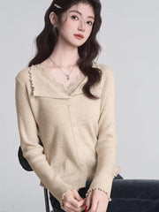 Woman wearing a beige ribbed knit cardigan with lace trim and a V-neck, with hands clasped.