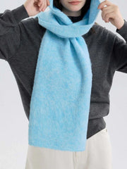 Close-up of a model wearing a gray sweater with a light blue hooded scarf around her neck.