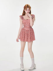 Full body shot of a woman in a red and white gingham dress, white lace socks, and white platform shoes.