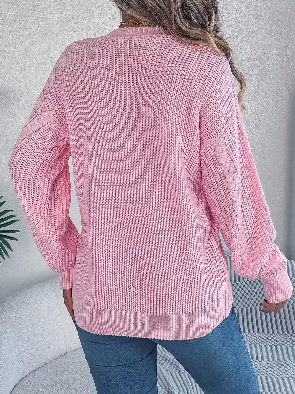 back view of a woman wearing a pink cable knit cardigan