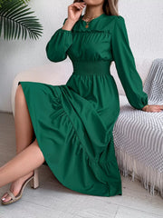 woman sitting on a couch wearing a long green dress