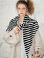 Model wearing a beige coat and black and white striped scarf