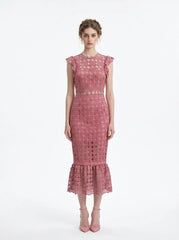 Woman wearing a pink lace dress with ruffled cap sleeves and a mermaid hemline, front view.