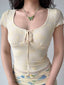 Close-up of a woman wearing a pale yellow mesh top with a floral print and a tie-front detail.
