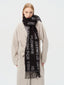 Woman wearing a black scarf with white text and a beige cardigan
