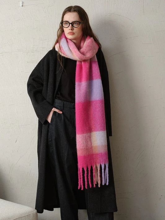 A woman wearing a dark coat and a long, brightly colored plaid scarf.