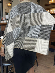 Back view of a woman wearing a geometric pattern knit poncho