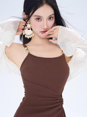 Close-up of a woman wearing a brown ruched mini dress and large white earrings.