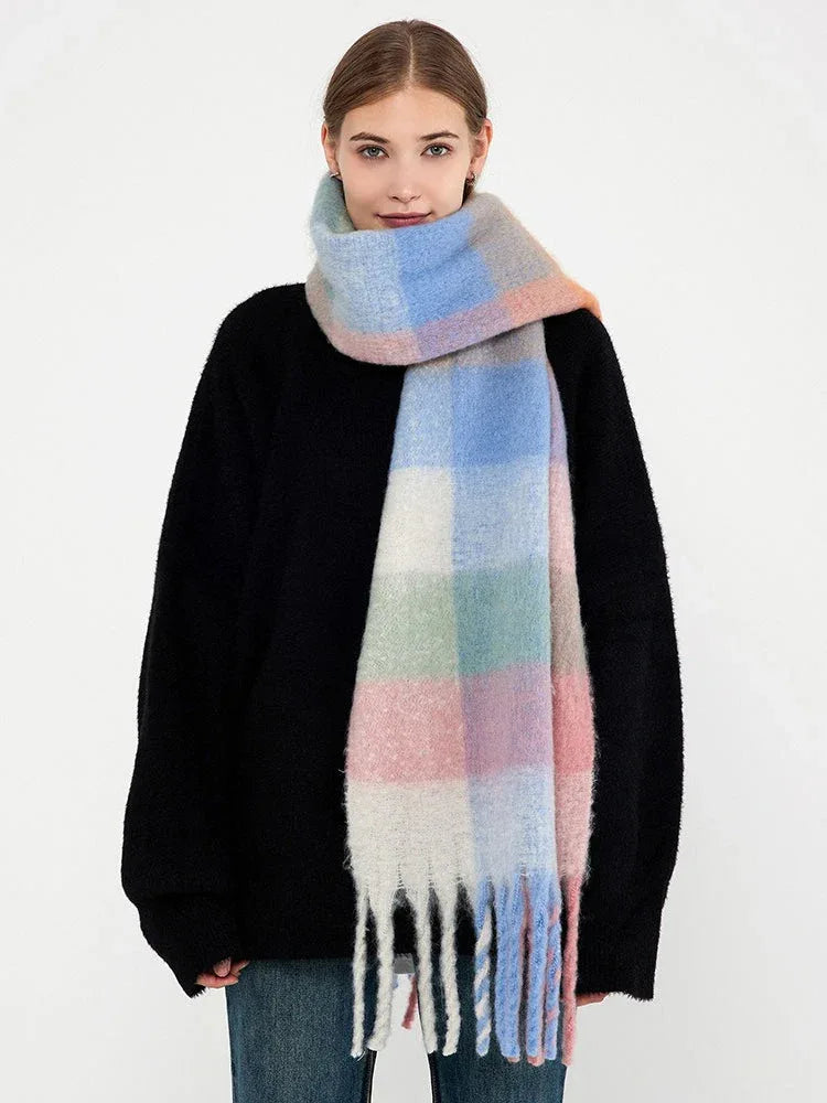 Woman in a black sweater and a pastel plaid scarf with fringe hanging down.