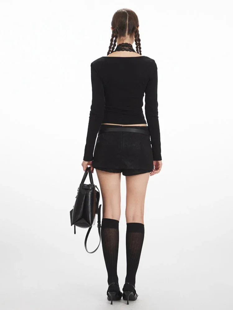 Back view of a woman wearing a black long-sleeve top and black mini skirt