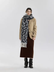Woman wearing a tan blazer over a brown skirt and a grey and black leopard print scarf with white fringe