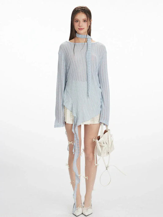 model wearing a light blue sheer knit sweater with an asymmetrical hem and a neck scarf, paired with a white lace skirt and white heels, holding a white handbag