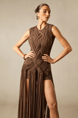 Model posing with hands on hips, showcasing the woven bodice and pleated skirt of a brown maxi dress.