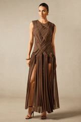 Full-length view of a brown maxi dress with a high slit, highlighting the pleated skirt and sleeveless design.