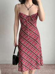 Full body shot of a woman in a red plaid midi dress, styled with a black necklace and handbag.