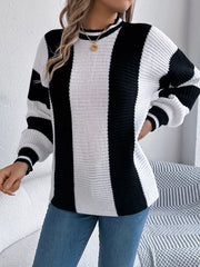 Woman wearing a black and white striped knit sweater and blue jeans, posing with her hand on her hip.