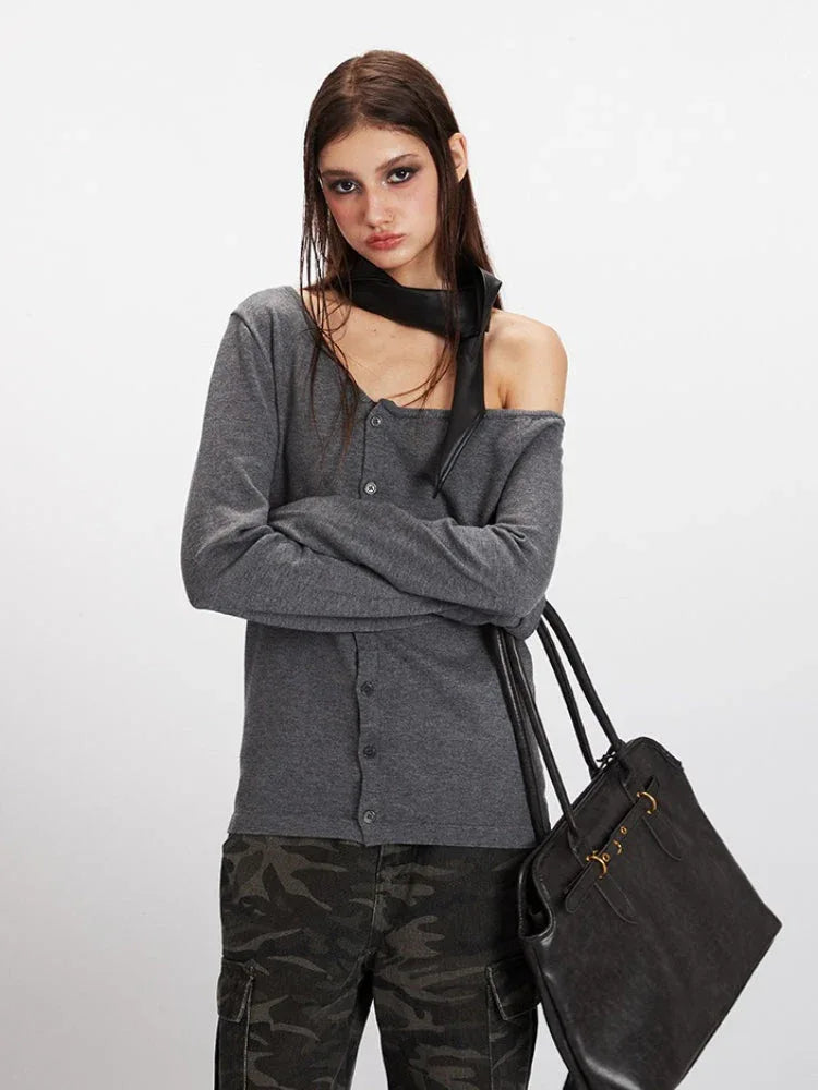 Close-up of a model wearing a grey off-the-shoulder knit top with a black scarf and camouflage cargo pants.