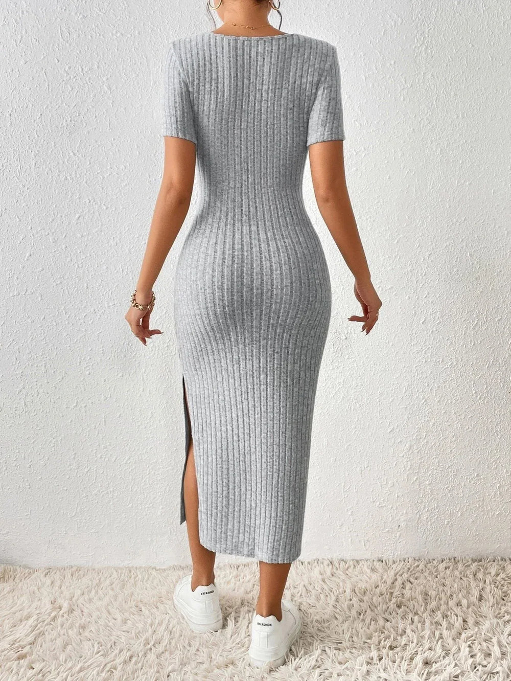 Back view of a woman wearing a grey ribbed knit midi dress with short sleeves and a square neckline.