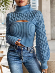 Woman sitting and wearing a blue knit turtleneck top with a cut-out detail and balloon sleeves, paired with blue jeans.