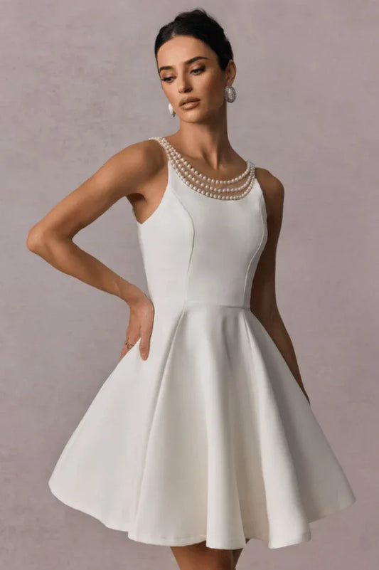 Woman wearing a short white A-line dress with a pearl neckline and open back