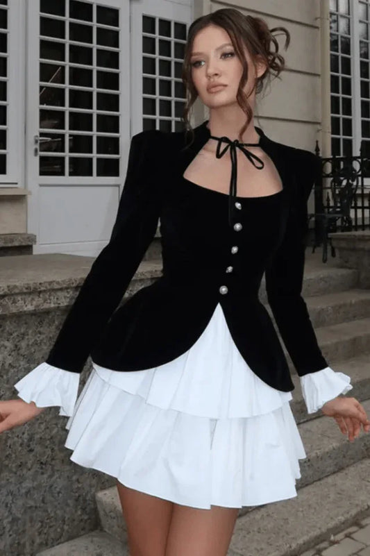 Woman wearing a black velvet jacket with a white ruffled skirt.