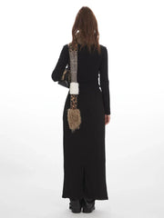 Back view of a model wearing a black long-sleeve top and a black maxi skirt with a drawstring waist and white star graphics, accessorized with a multi-patterned scarf.