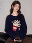Woman wearing a navy blue knit sweater with a popcorn graphic and Korean text, paired with brown pants.