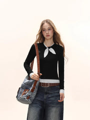 Close-up of a model wearing a black long-sleeve top with a white polka dot scarf detail and white polka dot cuffs, carrying a denim crossbody bag.