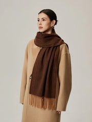 Woman wearing a brown scarf with orange detailing and a tan coat