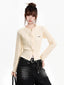 Woman wearing a cream cable knit cropped cardigan with black jeans and a black belt