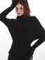 Close-up of a woman wearing a black turtleneck sweater with a textured knit fabric.