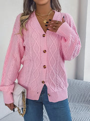 front view of a woman holding a white handbag and wearing a pink cable knit cardigan