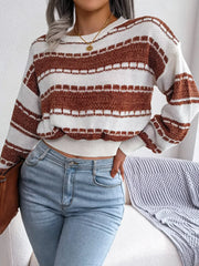 Woman wearing a brown and white striped cropped knit sweater, light wash jeans, and holding a brown clutch.