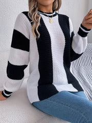 Woman wearing a black and white striped knit sweater and blue jeans, sitting on a couch.